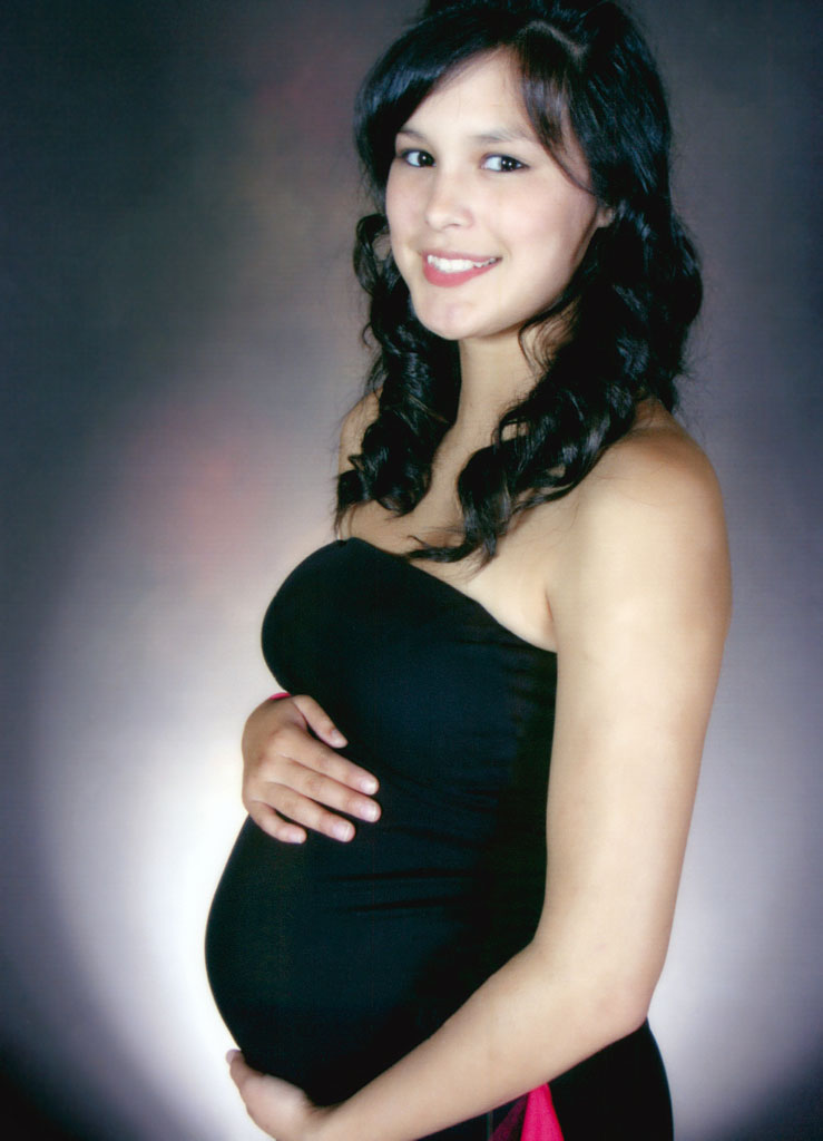 A pregnant woman in black dress smiling for the camera.