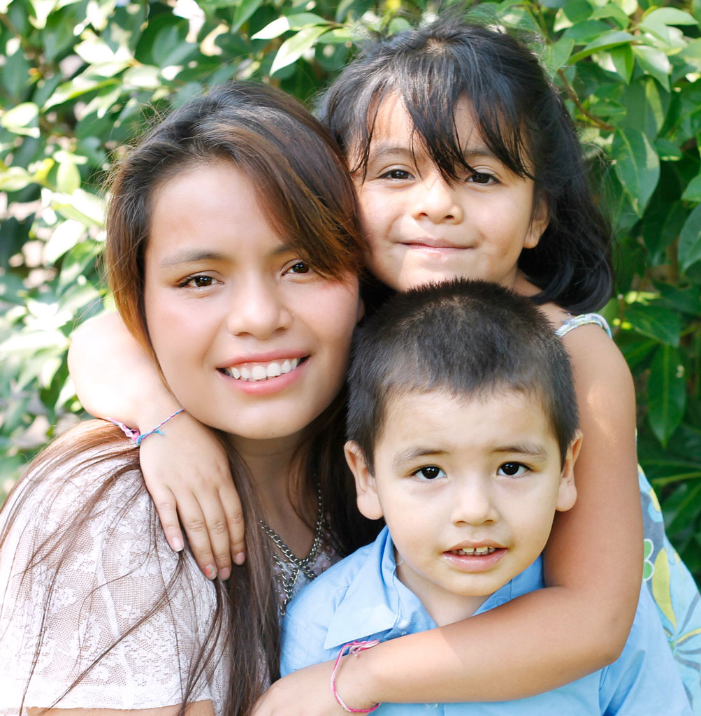 A woman and two children are smiling for the camera.