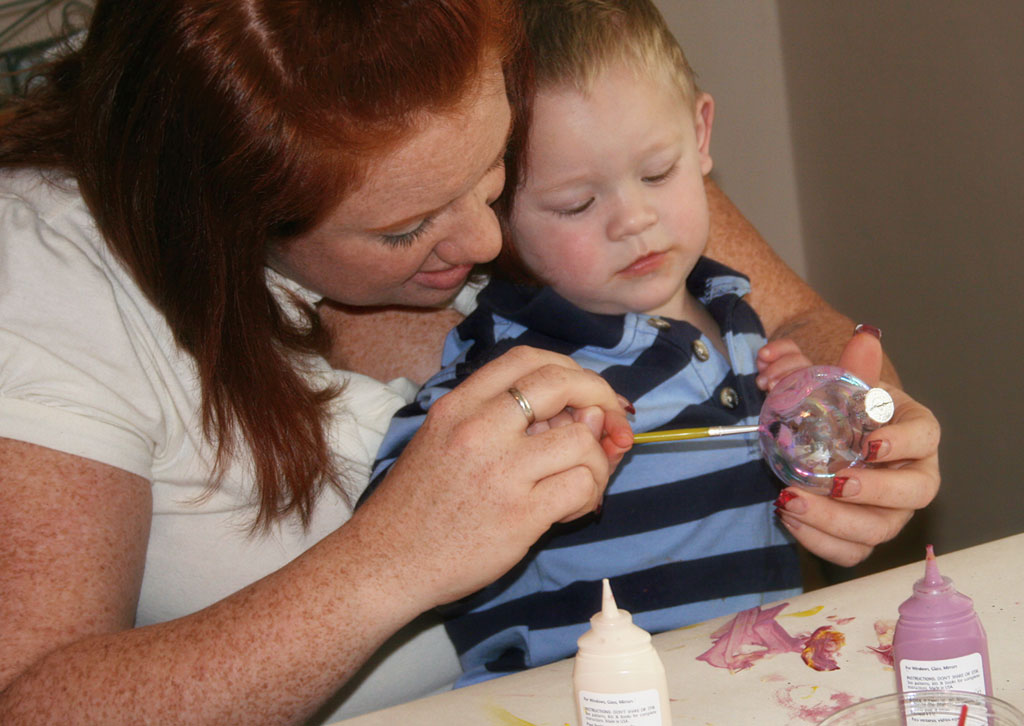 A woman and child are painting flowers on the table.