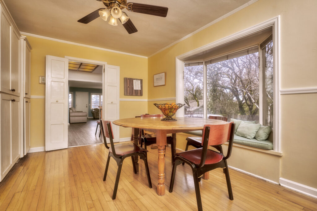 A dining room table with chairs and a ceiling fan.