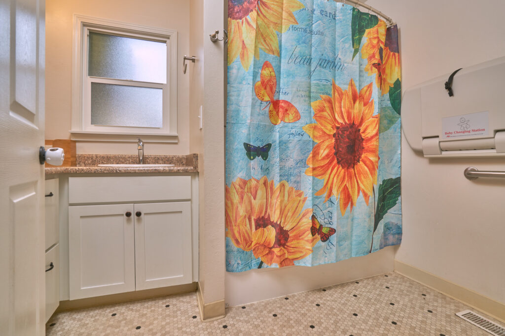 A bathroom with a shower curtain and tile floor.