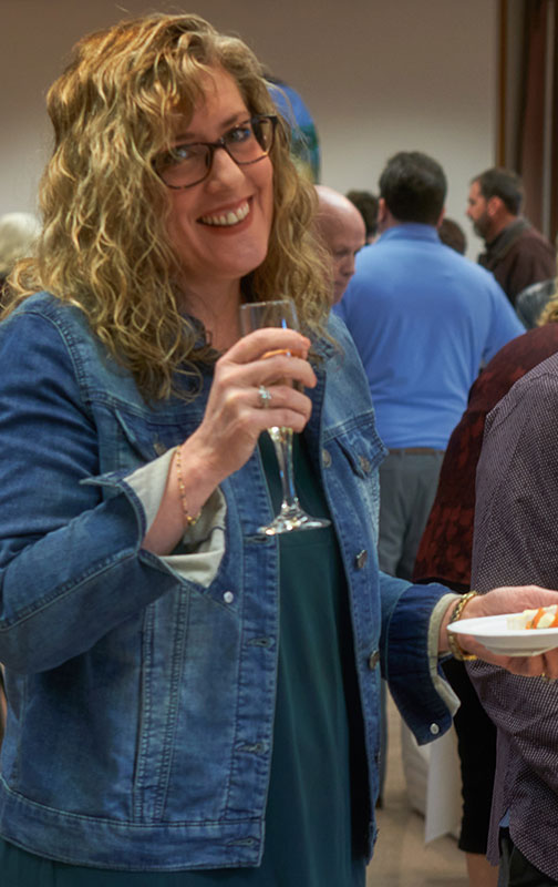 A woman holding a glass of wine and smiling.